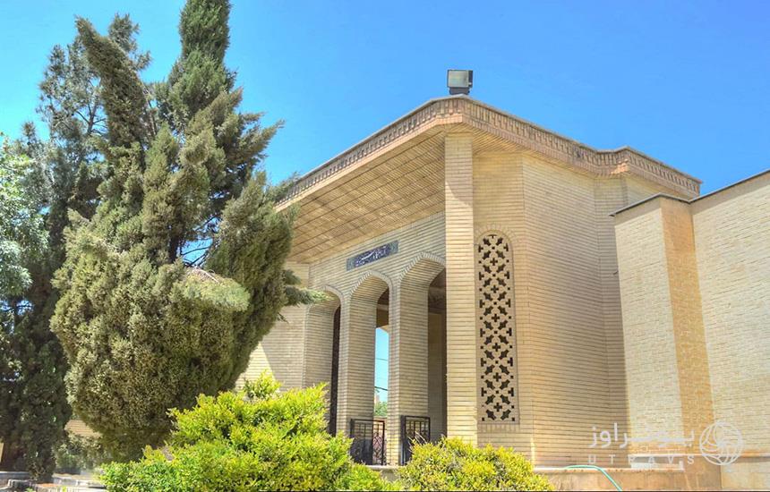آرامگاه «سیبویه» در شیراز که ساختمانی آجری است با معماری ساده و چند درخت کاج جلوی آن. 